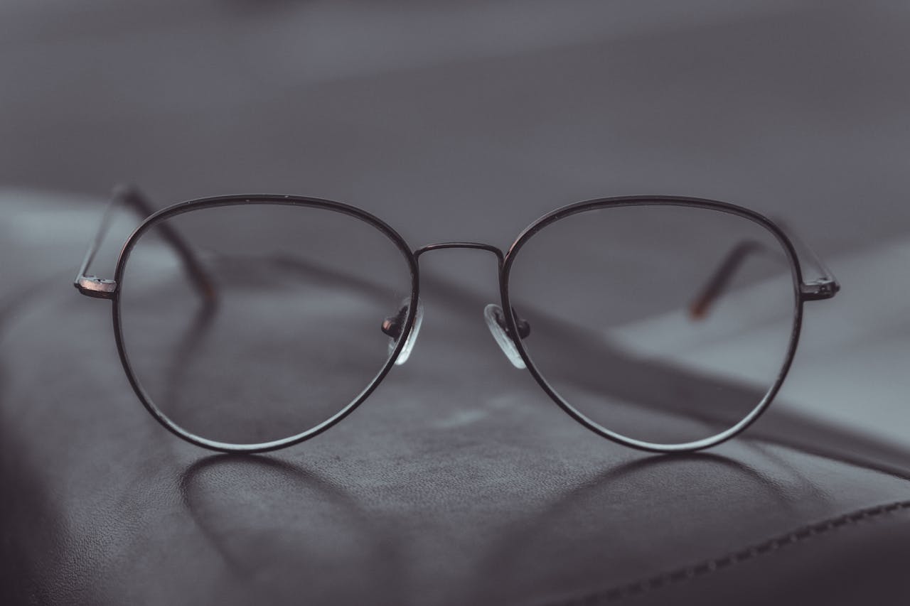 Contact Stylish aviator glasses resting on a leather surface, showcasing sleek design.